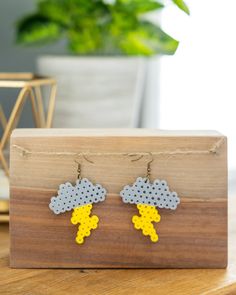 the earrings are made out of legos and have yellow, grey and white clouds