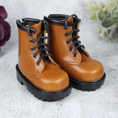 a pair of brown boots sitting on top of a white carpet next to flowers and plants