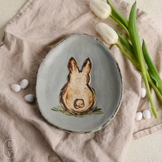 a plate with a rabbit on it next to some tulips and white flowers