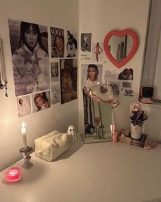 a white desk topped with pictures and a candle