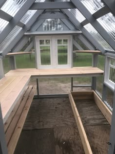 the inside of a greenhouse with benches and windows