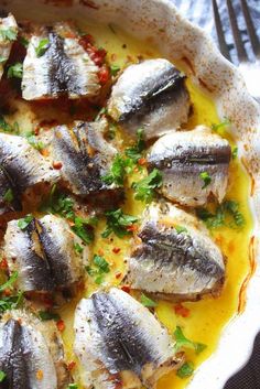 an image of fish with sauce and herbs in a dish on a tablecloth or cloth