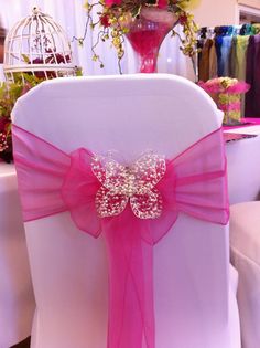 a chair covered in pink ribbon with a butterfly decoration on the front and back of it