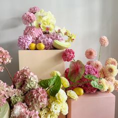 pink and yellow flowers are in front of a box with lemons on it, along with other colorful flowers