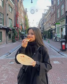 a woman is eating pizza on the street