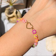 a woman's arm with a bracelet made out of flowers and hearts on it