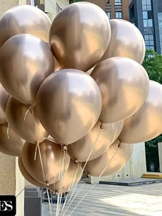 a bunch of metallic balloons are in the air on a street corner with buildings behind them