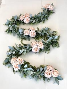 three pink roses and green leaves are arranged in the shape of letters s - v