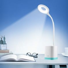 a desk lamp that is on top of a table next to a book and glasses