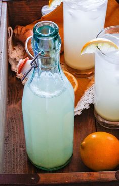 there is a pitcher and two glasses with lemonade on the table next to each other