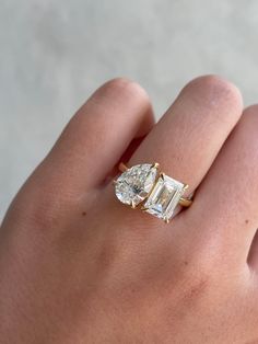 a woman's hand with a diamond ring on top of her finger, and the other hand holding an engagement ring