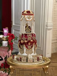 a three tiered wedding cake with red and gold decorations