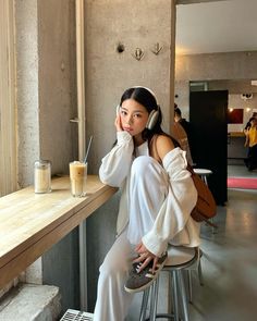 a woman sitting at a table with headphones on her ears and looking off to the side