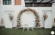 a white chair sitting in front of a floral arch