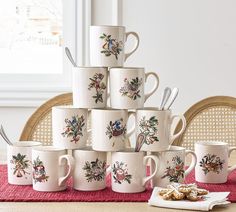 a stack of coffee cups sitting on top of a table next to a pile of cookies