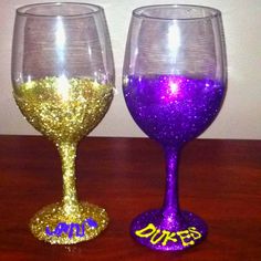 two purple and gold wine glasses sitting on top of a wooden table