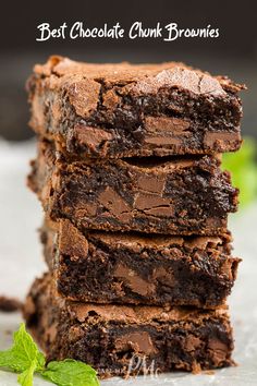 chocolate chunk brownies stacked on top of each other with mint sprigs in the background