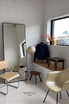 an empty room with chairs, mirrors and a coat hanging on the window sill