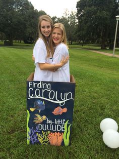 two girls standing in front of a cardboard sign