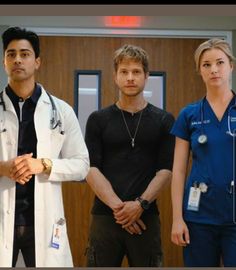 three doctors standing in front of a wall with the door open and looking at the camera