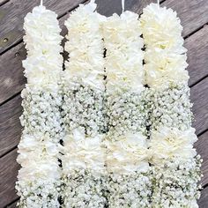 white flowers are arranged in rows on a wooden surface with string attached to the stems