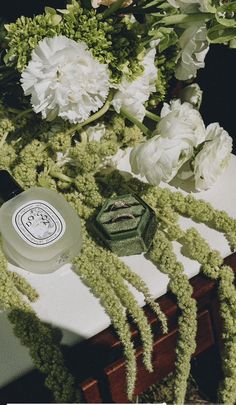 flowers and candles are sitting on a table with green moss growing around the top of it