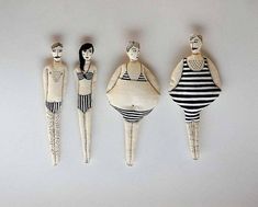 three wooden dolls are standing next to each other on a white surface with black and white stripes