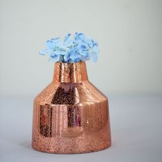 a copper vase with blue flowers in it