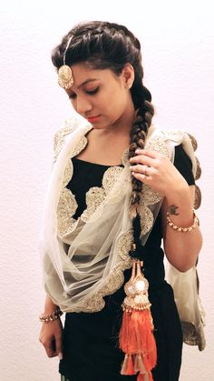 a woman with long hair wearing a black dress and orange tassels on her head