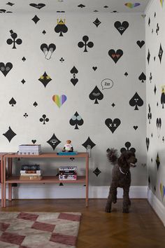 a dog standing in front of a wall with playing cards on it's walls