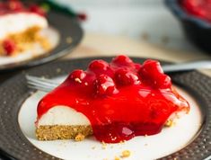 a piece of cheesecake covered in cherries on a black plate with a fork