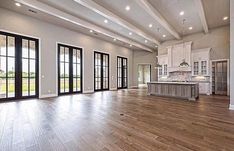 an empty living room with wood floors and large windows in the middle of the room