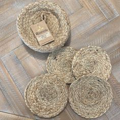 four jute coasters sitting on top of a wooden floor