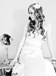 a woman in a white dress is looking at her reflection in a mirror while sitting on a table