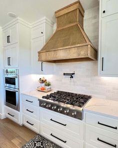 a stove top oven sitting inside of a kitchen next to white cupboards and drawers