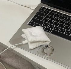 a laptop computer sitting on top of a white desk next to a wedding band and ring