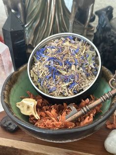 a bowl filled with dried flowers on top of a wooden table next to other items