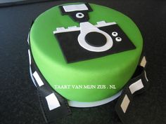 a green cake with black and white designs on it's side, sitting on a table