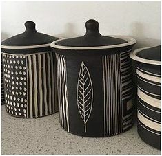 four black and white canisters lined up against a wall