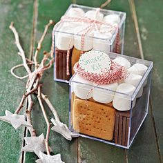 two clear boxes filled with cookies and marshmallows on top of a table