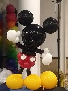 a mickey mouse balloon is standing in front of balloons