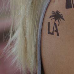 the back of a woman's shoulder with palm trees and lighthouses on it