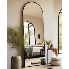 a mirror sitting on top of a wooden floor next to a potted plant