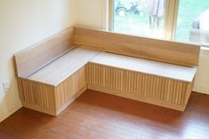 a wooden bench sitting next to a window on top of a hard wood floored floor