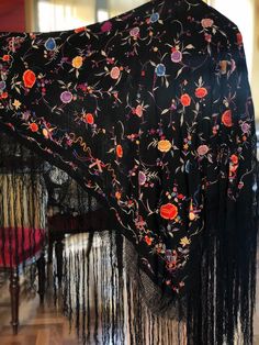 A magnificent Manton de Manila shawl made of black silk crepe fabric then heavily embroidered with colourful silk thread.  The embroidery is so well done you can barely tell which is the right side. The shawl is covered in embroidered flowers and leaves and around the edges are unusual depictions of musical symbols and bows. Quite a spectacular piece. In excellent condition  Measures 42" x 42" with a 20" woven fringe Black Pashmina Shawl With Intricate Embroidery, Black Embroidered Pashmina Shawl, Black Intricate Embroidery Pashmina Shawl, Black Floral Embroidered Shawl Dupatta, Black Embroidered Silk Shawl, Embroidered Black Pashmina Shawl, Black Floral Embroidered Dupatta Shawl, Black Shawl Dupatta With Floral Embroidery, Black Silk Dupatta With Floral Embroidery