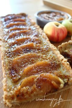 an apple pie is on a cutting board next to some fruit