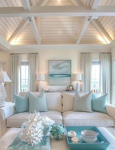 a living room filled with white furniture and lots of blue pillows on top of it