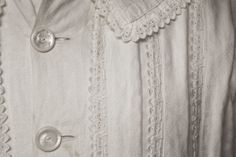 an old photo of a woman's shirt with buttons and lace on the collar