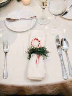 the table is set with silverware and candy canes