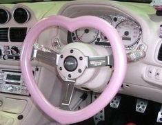 the interior of a car with pink steering wheel and dash stick, including an instrument